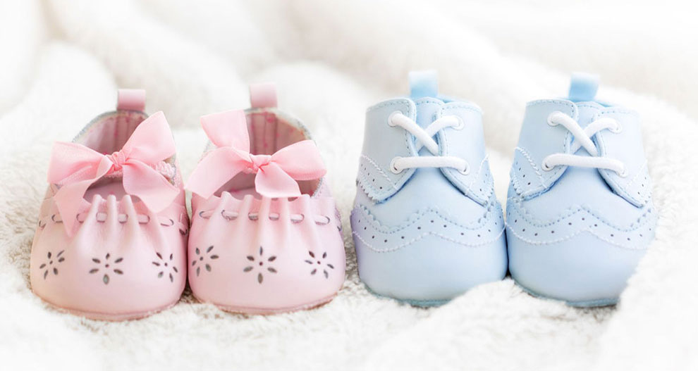 Two pairs of baby shoes, one pink with flower perforations and a bow, the other blue with lace-up design and decorative perforations.