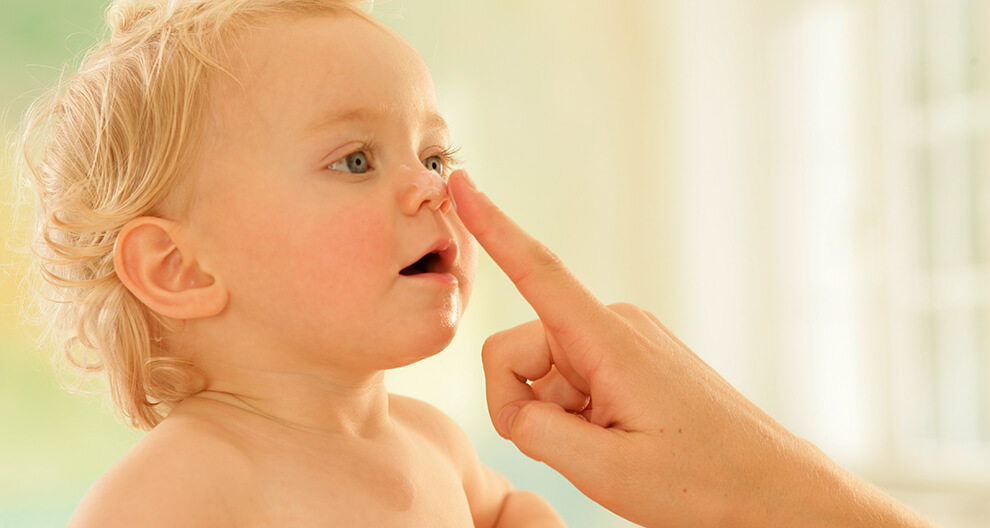 A child with curly hair is being touched by a human finger.
