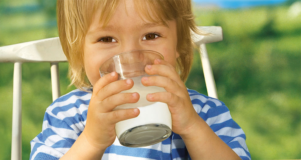 A child in a blue-striped shirt is drinking from a clear glass.