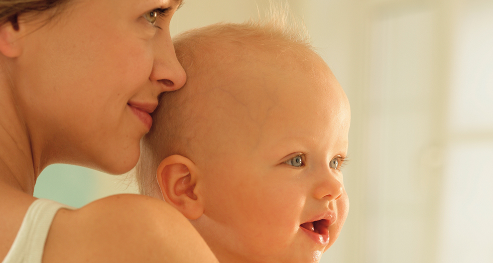 A woman lovingly holds a baby close to her face.
