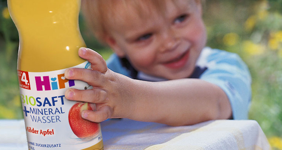 A child is holding a bottle of apple-flavored mineral water.