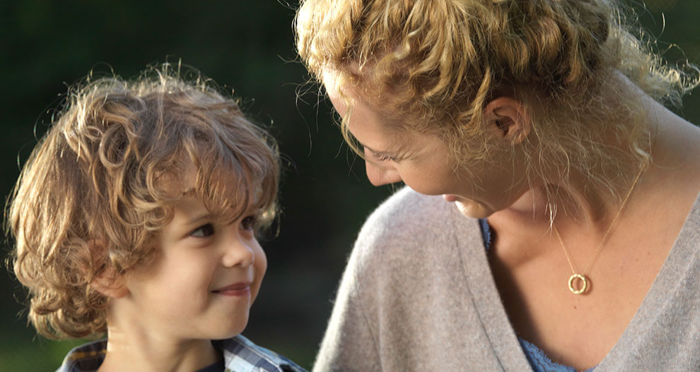 A woman and a young boy share a moment of connection outdoors.