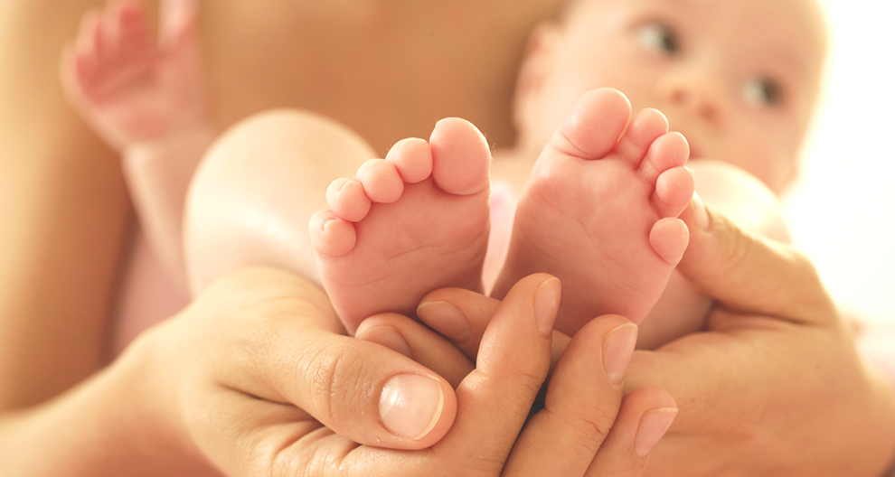 A baby's feet are held gently by a pair of hands.