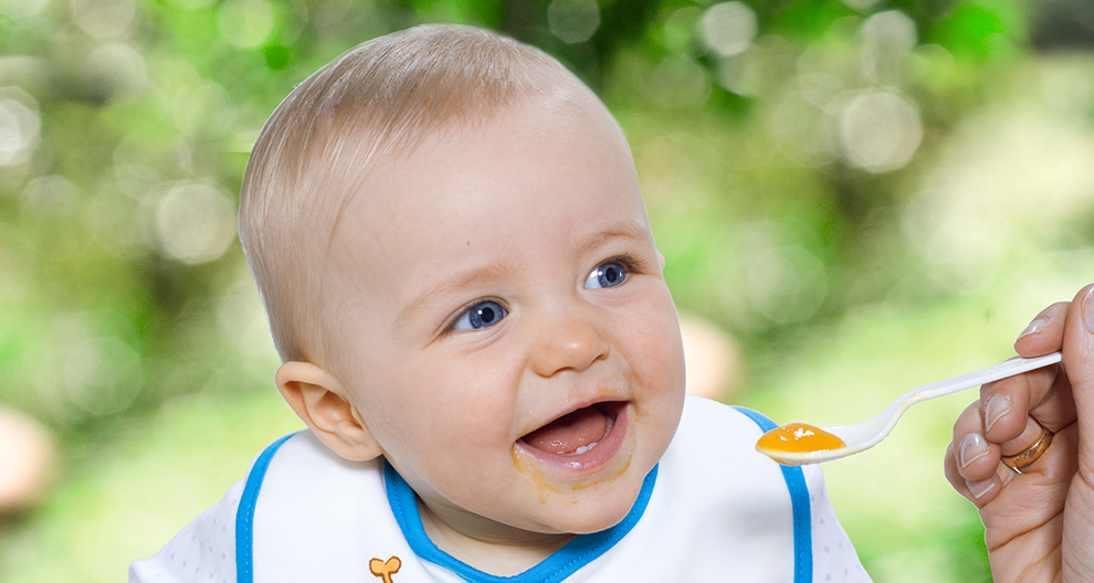 A baby with a spoon of food.