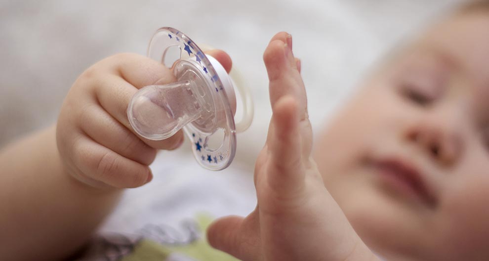La mano di un bambino tiene un ciuccio.
